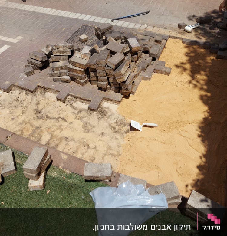 אבנים משתלבות, חול וכלי עבודה באתר שיפוץ